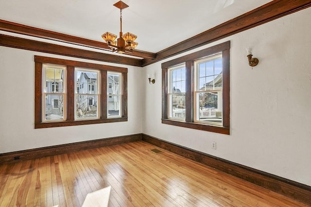 spare room featuring wood-type flooring and a chandelier