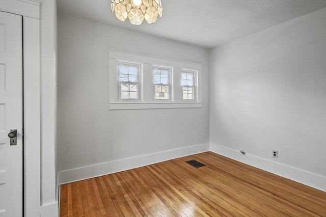 unfurnished room with hardwood / wood-style floors and a notable chandelier