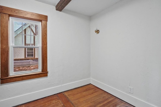 empty room with beam ceiling and hardwood / wood-style floors