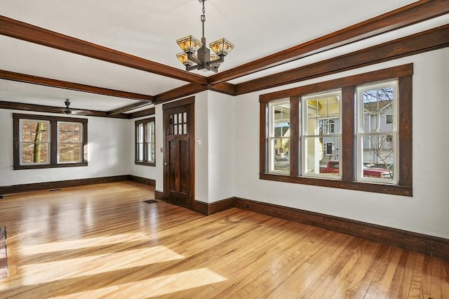 spare room featuring a notable chandelier, beam ceiling, and light hardwood / wood-style floors