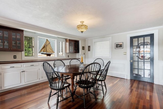 dining space featuring crown molding, dark wood finished floors, and wainscoting