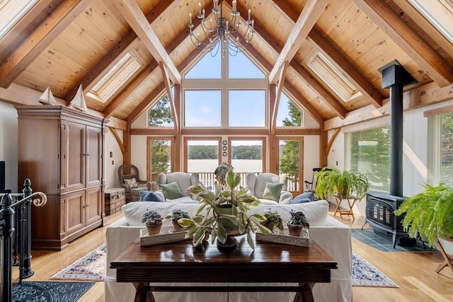 living area with a wood stove, a skylight, plenty of natural light, beamed ceiling, and high vaulted ceiling