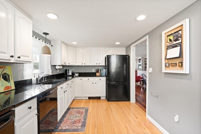 kitchen with black appliances, a sink, light wood-style floors, white cabinets, and recessed lighting