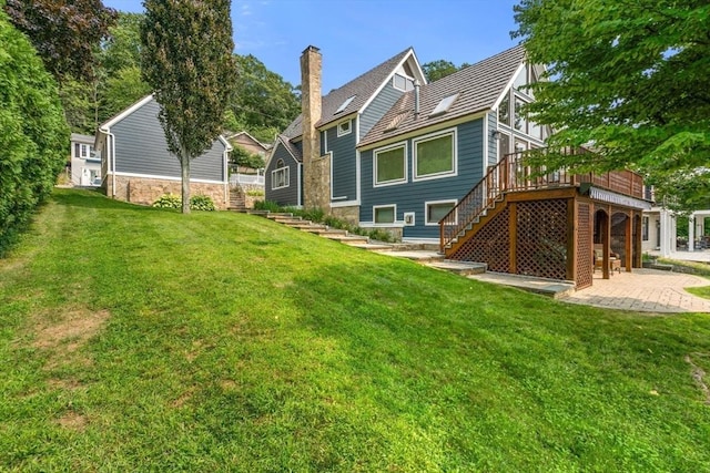 back of property featuring stairway, a deck, a patio, and a lawn