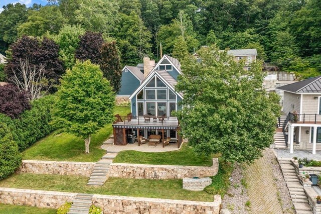 back of house with stairway, a patio area, a wooden deck, a lawn, and a chimney