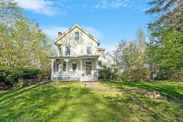 view of front of house with a porch, a chimney, and a front yard