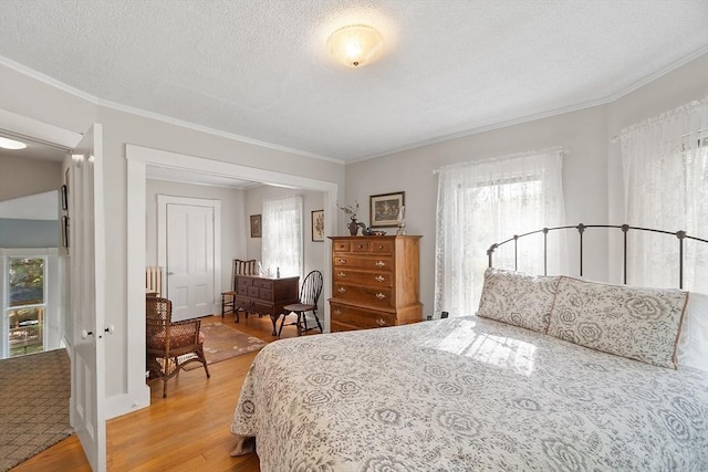 bedroom with crown molding, a textured ceiling, multiple windows, and light wood-style floors