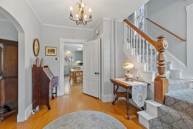 foyer entrance featuring stairs, arched walkways, baseboards, and light wood-style floors