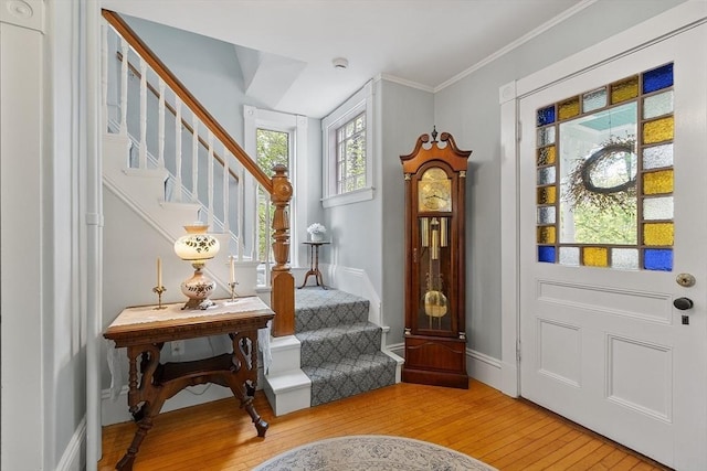 entryway with crown molding, light wood-type flooring, baseboards, and stairs
