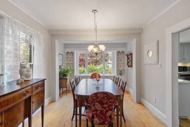 dining room featuring baseboards, a healthy amount of sunlight, light wood finished floors, and a chandelier