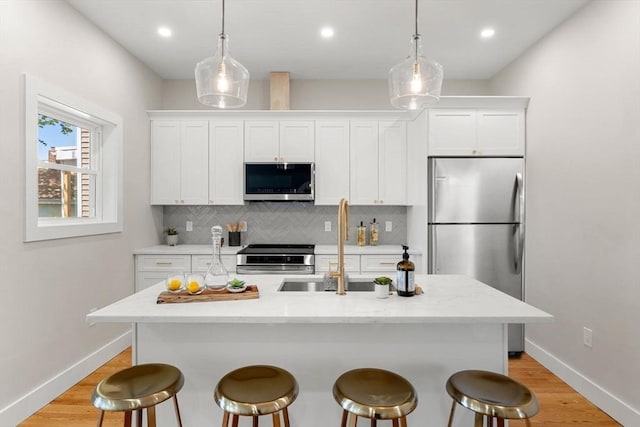 kitchen featuring baseboards, appliances with stainless steel finishes, decorative backsplash, and a kitchen bar
