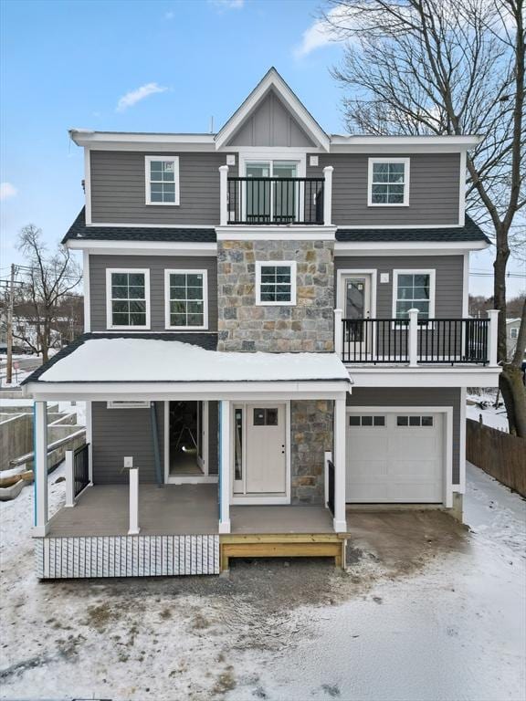 view of front of house featuring covered porch, stone siding, fence, an attached garage, and a balcony
