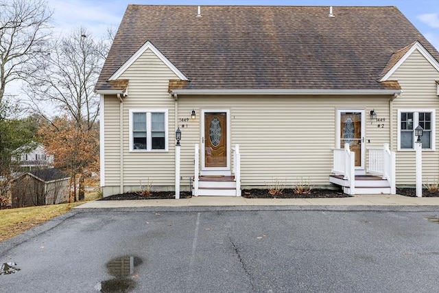 new england style home featuring roof with shingles