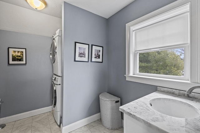 bathroom featuring marble finish floor, stacked washing maching and dryer, vanity, and baseboards