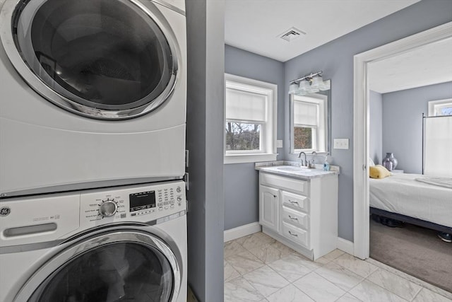 laundry area featuring visible vents, laundry area, marble finish floor, stacked washer / drying machine, and a sink