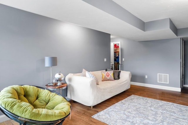 living area featuring visible vents, wood finished floors, and baseboards