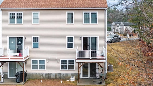 back of house featuring central AC unit and a shingled roof