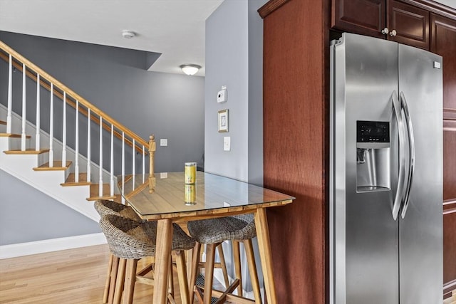 kitchen with light wood finished floors, baseboards, and stainless steel fridge with ice dispenser