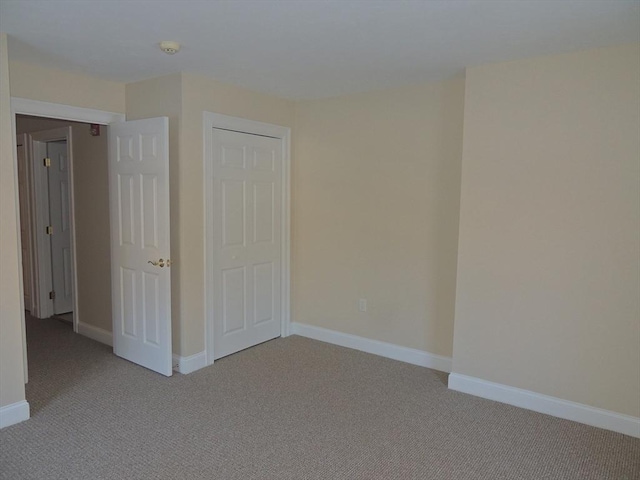 unfurnished bedroom featuring light colored carpet and a closet