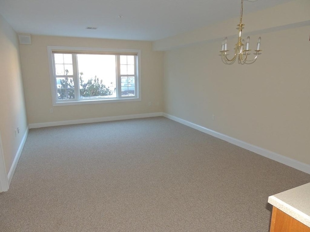 spare room with carpet floors and a notable chandelier