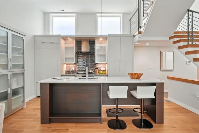 91 Kirkland St Unit 91, Cambridge, MA 02138 - bar area with wall chimney range hood, a high ceiling, decorative backsplash, healthy amount of natural light, and stairs