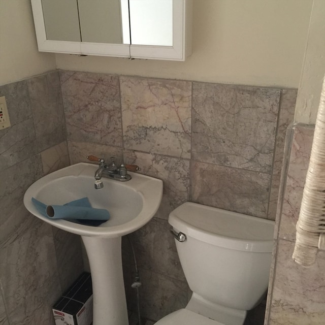 bathroom with toilet and tile walls