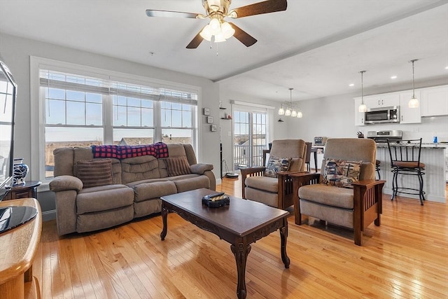 living room with ceiling fan with notable chandelier and light wood-type flooring