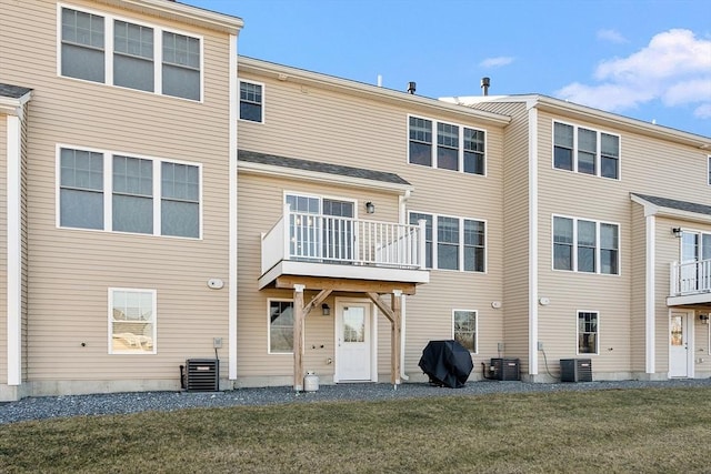 rear view of property with central air condition unit and a lawn