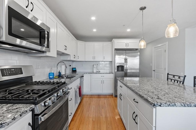 kitchen with pendant lighting, a center island, white cabinets, sink, and appliances with stainless steel finishes