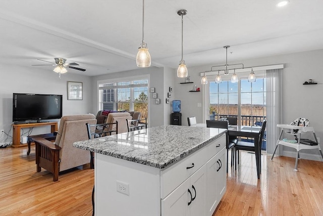 kitchen featuring white cabinets, light hardwood / wood-style flooring, ceiling fan, light stone countertops, and decorative light fixtures