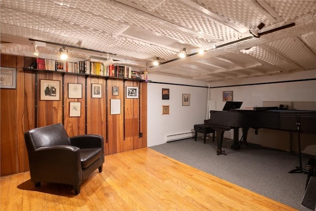 living area featuring carpet flooring, baseboard heating, and wood walls