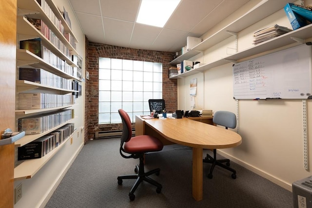 office area with brick wall, carpet flooring, and a drop ceiling