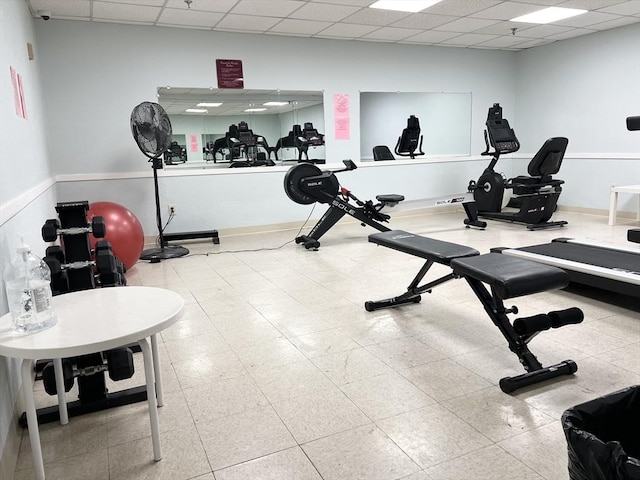 gym featuring baseboards and a drop ceiling