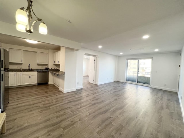 kitchen featuring dark wood finished floors, dark countertops, open floor plan, and appliances with stainless steel finishes