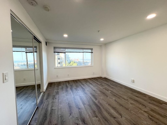 unfurnished bedroom featuring dark wood finished floors, recessed lighting, baseboards, and a closet