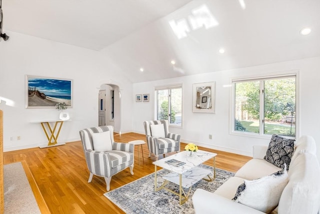 living room with arched walkways, vaulted ceiling, light wood-type flooring, and recessed lighting