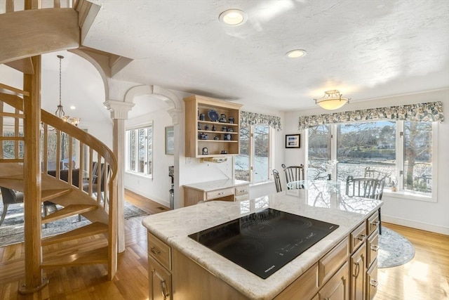 kitchen featuring light wood-type flooring, decorative columns, baseboards, open shelves, and black electric stovetop