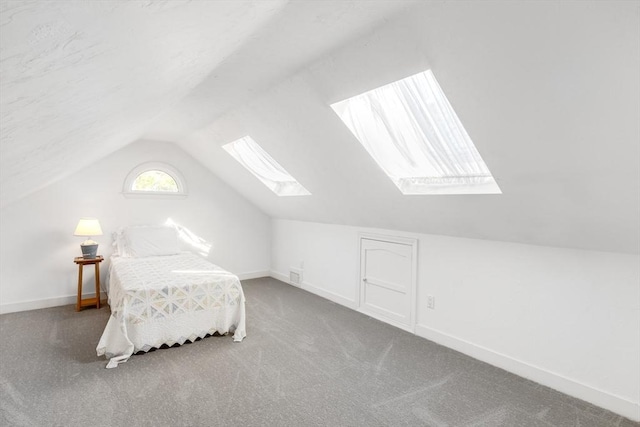 carpeted bedroom with baseboards, vaulted ceiling with skylight, and visible vents