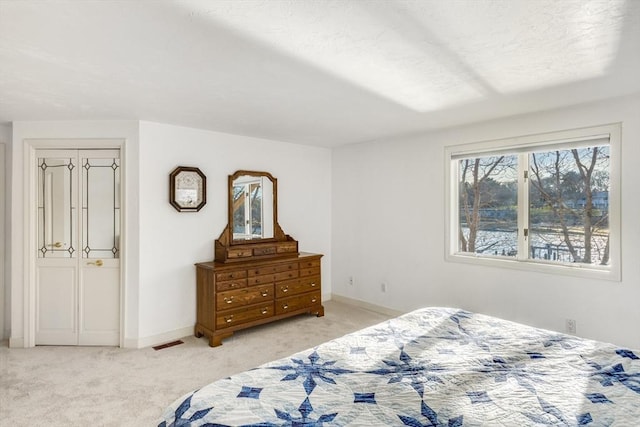 bedroom featuring visible vents, light carpet, and baseboards