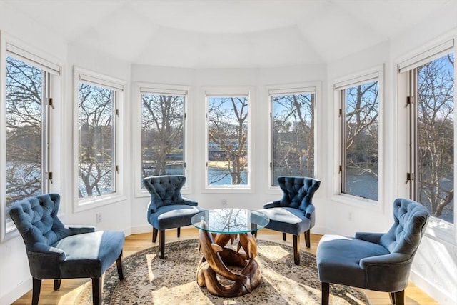 sunroom featuring lofted ceiling, a healthy amount of sunlight, and wood finished floors