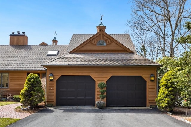 view of front of house featuring an attached garage, aphalt driveway, a chimney, and roof with shingles