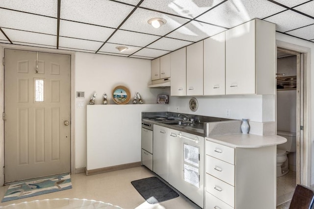 kitchen with white cabinets, baseboards, a sink, and a drop ceiling