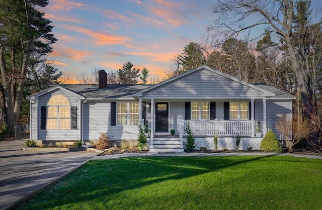 ranch-style house with a porch and a yard