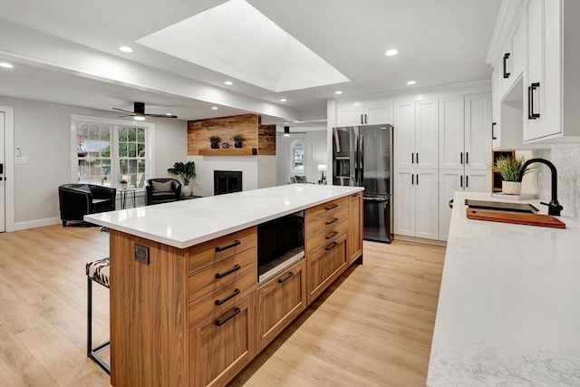 kitchen featuring white cabinetry, light stone counters, light wood-type flooring, and appliances with stainless steel finishes