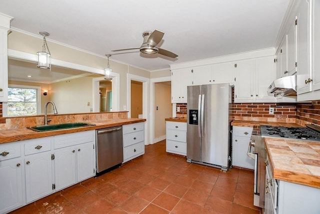 kitchen featuring decorative backsplash, stainless steel appliances, sink, decorative light fixtures, and white cabinetry