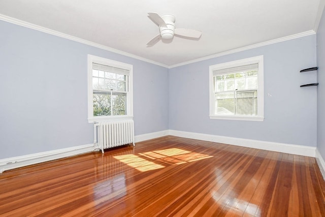 unfurnished room with a wealth of natural light, radiator heating unit, and wood-type flooring