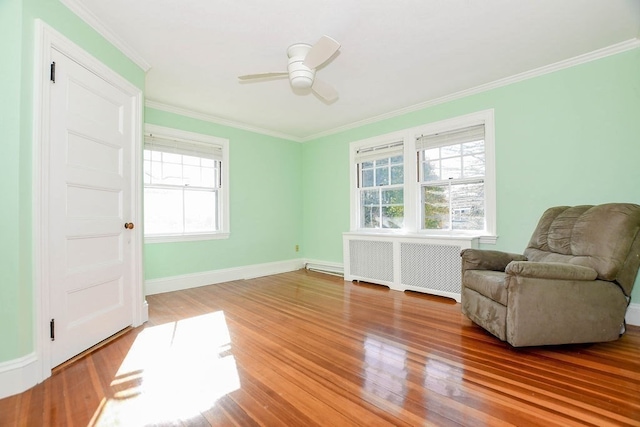 sitting room featuring hardwood / wood-style floors, crown molding, radiator heating unit, and ceiling fan