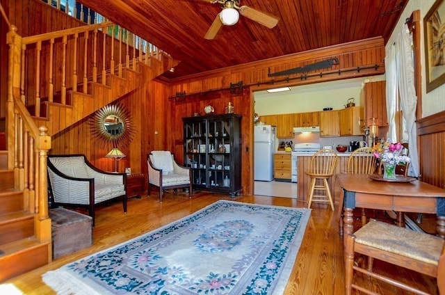 interior space featuring wooden walls, light hardwood / wood-style flooring, wood ceiling, and ceiling fan