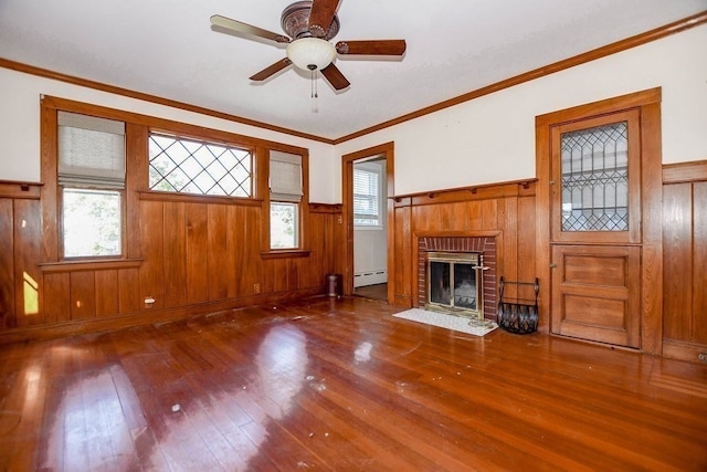 unfurnished living room with a baseboard radiator, a fireplace, ceiling fan, crown molding, and hardwood / wood-style flooring