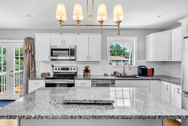 kitchen featuring a kitchen island, a wealth of natural light, decorative light fixtures, and stainless steel appliances